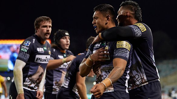 Len Ikitau celebrates with Brumbies teammates after scoring.