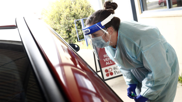 Medical professionals perform COVID testing at a drive-through clinic.