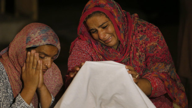 Women mourn beside the dead body of their family member Sabir Hussain, who died after their house collapsed after a powerful earthquake in Sahang Kikri, northeast Pakistan