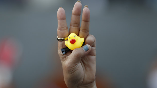 The three-finger protest gesture is flashed by a protester while holding a yellow duck, which has become a  symbol of resistance.