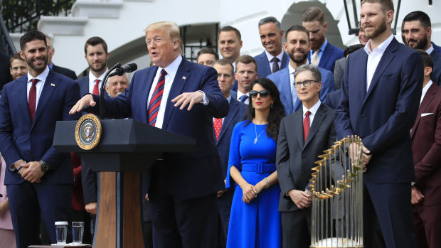 President Trump addresses the crowd alongside the Major League trophy.