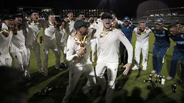 Steve Smith wears glasses in the middle of the team huddle as the Australians celebrate victory at Old Trafford.