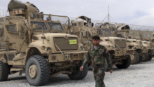 An Afghan soldier walks past vehicles left by the American military. 