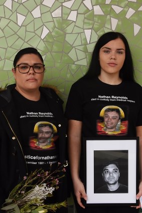 Taleah Reynolds (left) and Makayla Reynolds (right) hold a portrait of their brother Nathan in front of the NSW Coroners Court on Wednesday.
