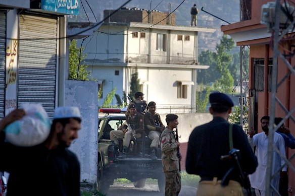 Pakistan army soldiers and police officers patrol past the house, background, where it is believed al-Qaida leader Osama bin Laden lived in Abbottabad, Pakistan.