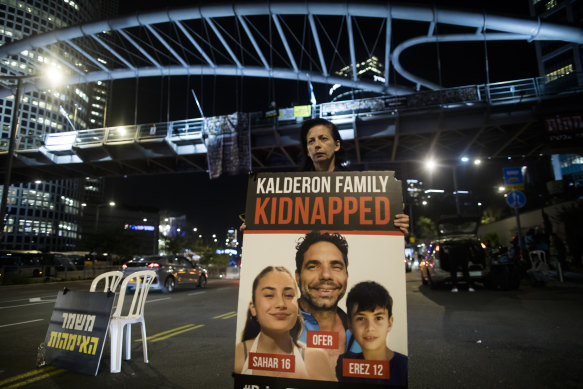 A woman holds a sign showing a family held hostage in the Gaza Strip in Tel Aviv.