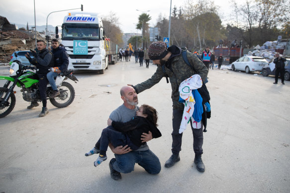 A man carries a young survivor who was found in a collapsed building Hatay, Turkey.