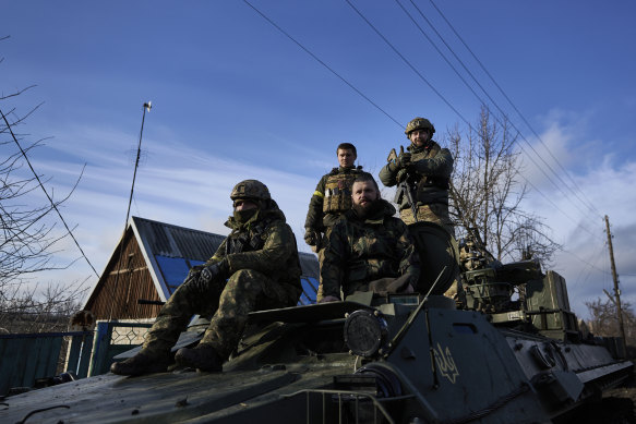 Ukrainian soldiers ride atop an armoured vehicle near Bakhmut.