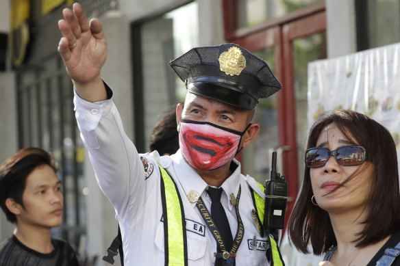 A security guard wearing a protective mask assists a woman in Manila. Philippine President Rodrigo Duterte authorised sweeping quarantines to fight the coronavirus. 