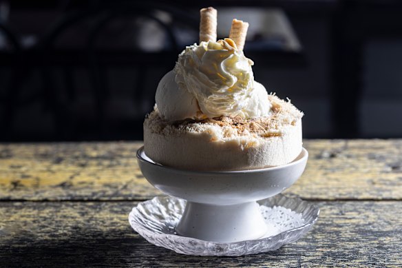 Coconut ice-cream scooped into a coconut shell topped with whipped cream and a drizzle of Vietnamese coffee.