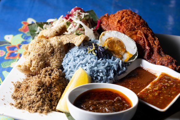Nasi kerabu, um bolinho de arroz tingido de azul com flor de borboleta, acompanhado de coco torrado, bolachas de peixe, repolho picado, sambals e frango frito, é um prato de assinatura.