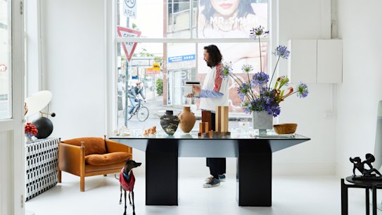 Ben Mooney with his greyhound, Goody, in the front room of his store. Local florist and designer Hattie Molloy designed the large “Ixia” vase and also created the agapanthus installation.