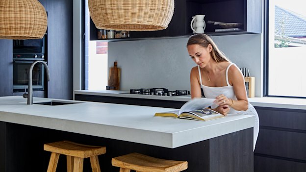 “Because of the open-plan living, and because there’s only two of us, we have all our meals at the kitchen bench,” says Kate. “It is one of my favourite spots.”  The kitchen bench is Caesarstone in “Cloudburst Concrete”, the lampshades are from Ur Place and the wooden stools are by Uniqwa Collections.  