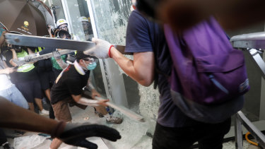 Demonstrators use metal bars to break a window at the Legislative Council building.