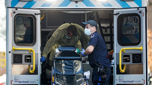 Medical workers load oxygen and disinfect surfaces of an ambulance outside a COVID-19 testing side at Elmhurst Hospital Centre.