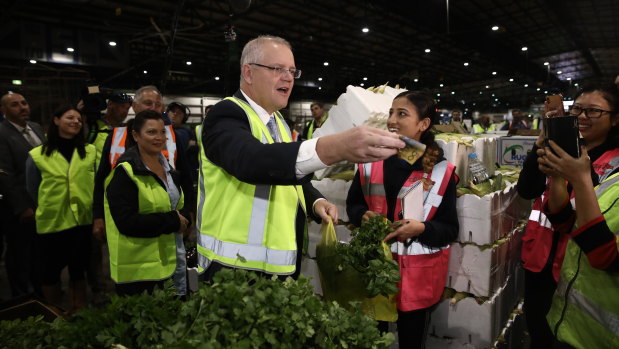 Prime Minister Scott Morrison, wife Jenny and Federal Liberal Candidate for Reid Fiona Martin buy coriander at the Sydney Markets in Homebush.