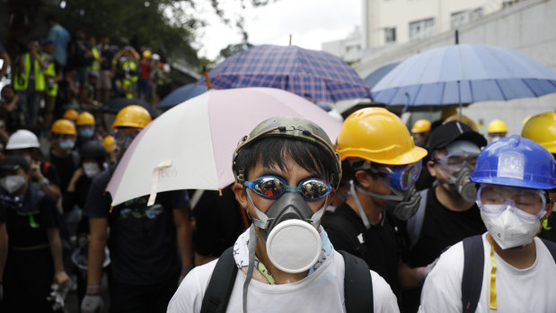 Protesters wearing gas masks and helmets stand near the police headquarters during a demonstration in Hong Kong, China, on Friday.