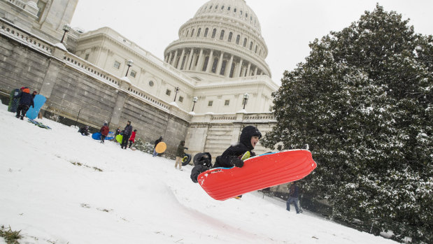 Two children go over a ramp as they sled on Capitol Hill, Washington. 
