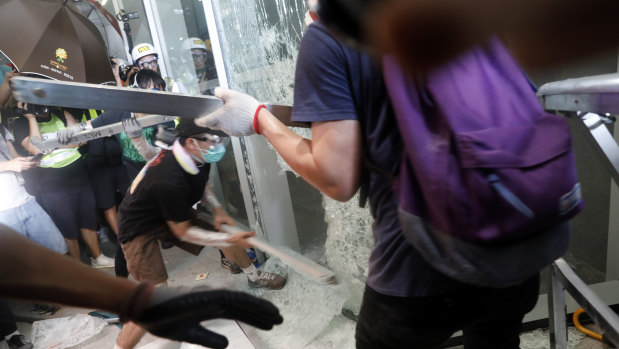 Demonstrators use metal bars to break a window at the Legislative Council building.