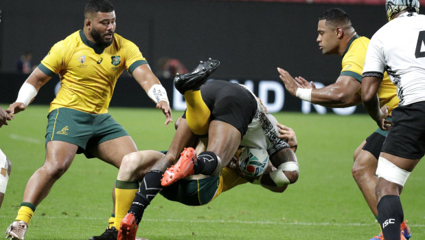 Hit-and-run: David Pocock finishes under a Fijian attacker in defence.