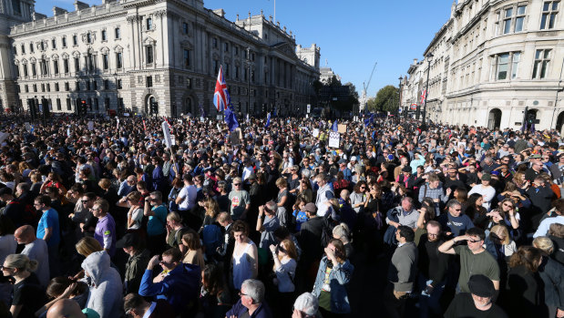 A Union flag, also known as a Union Jack, stands above crowds of demonstrators as they listen to speeches on Parliament Square following the anti-Brexit People's Vote march in London, UK.