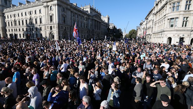 A Union flag, also known as a Union Jack, stands above crowds of demonstrators as they listen to speeches on Parliament Square following the anti-Brexit People's Vote march in London, UK.