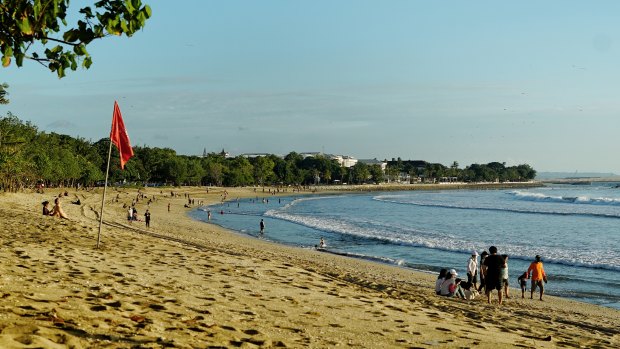 Visitors return to the beach at Kuta.