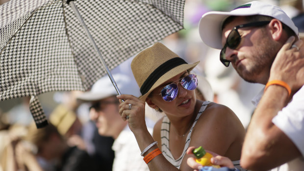 Spectators shade themselves from blistering sun at Wimbledon earlier this month.