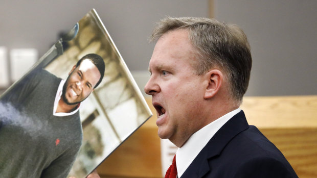 Assistant District Attorney Jason Hermus waves a photo of Botham Jean at the jury during the trial.