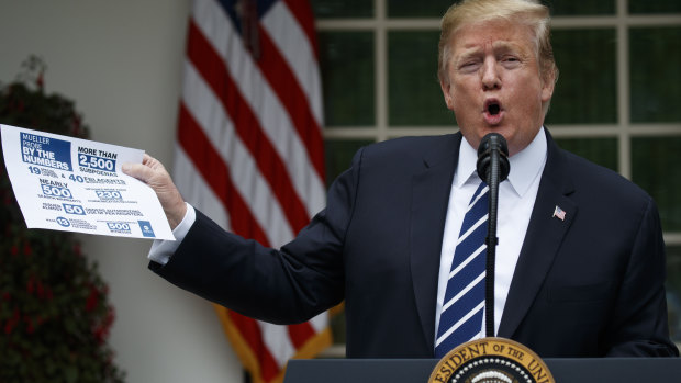 US President Donald Trump brandishes a sheet about the Mueller report at a surprise press conference in the White House Rose Garden. 