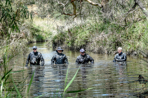 Police wade through chest-deep water in the search for missing mother Ju Zhang on Monday.