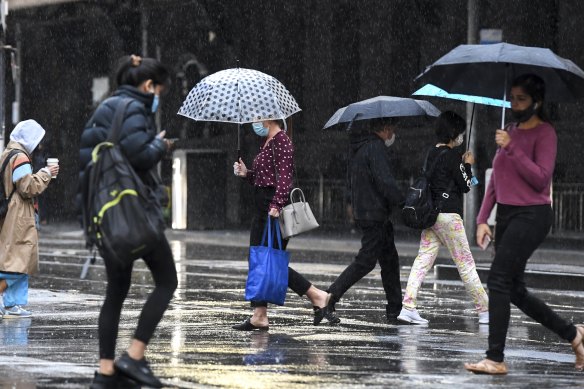 Commuters try to avoid the rain in Melbourne on Friday. 