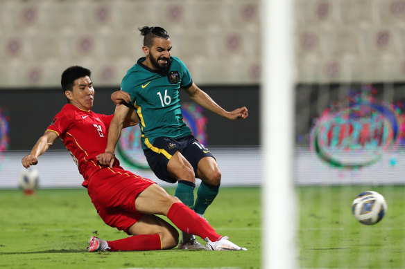 Aziz Behich of Australia is challenged by Gang Wang of China during their 1-1 draw.