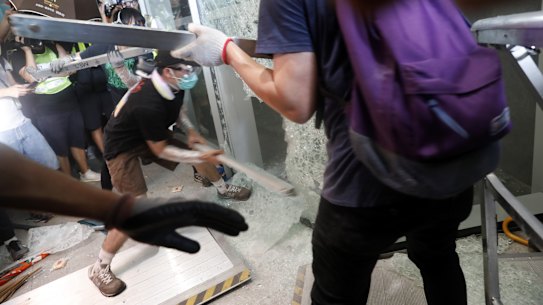 Demonstrators use metal bars to break a window at the Legislative Council building.