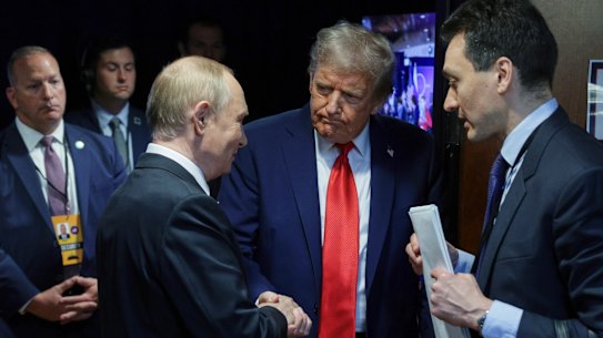 Trump and Putin shake hands.