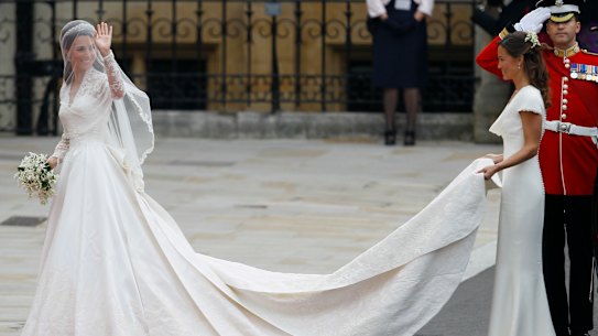 Kate Middleton em seu vestido de noiva Alexander McQueen se preparando para entrar na Abadia de Westminster, com sua irmã Pippa carregando sua cauda.