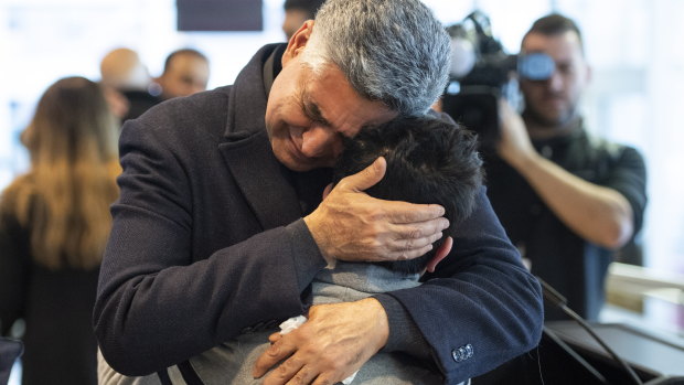 Ryan Pourjam, 13, son of Mansour Pourjam, is embraced by family friend Mahmoud Rastgou, after a ceremony at Carleton University in Ottawa.