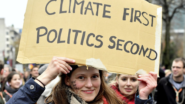 A demonstrator holds a placard which reads 'climate first, politics second' during a 'Claim the Climate' march in Brussels, on Sunday.