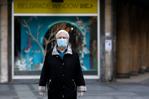 An elderly woman wearing a mask against the spread of the new coronavirus walks during a curfew in downtown Belgrade, Serbia.
