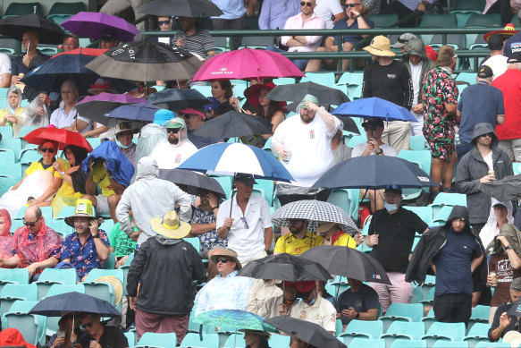 Fans reach for the umbrellas on a wet day at the SCG. 