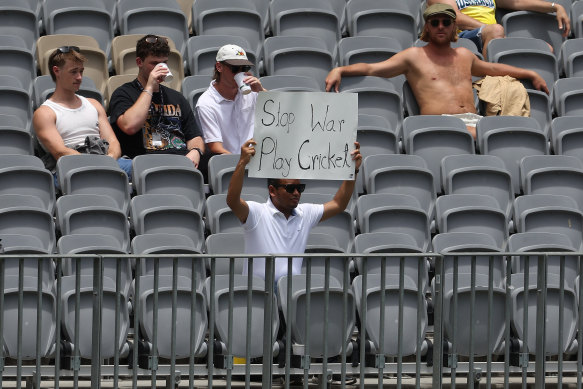 A supporter holds up a sign reading “Stop War Play Cricket” during day three of the Men’s First Test match between Australia and Pakistan at Optus Stadium.