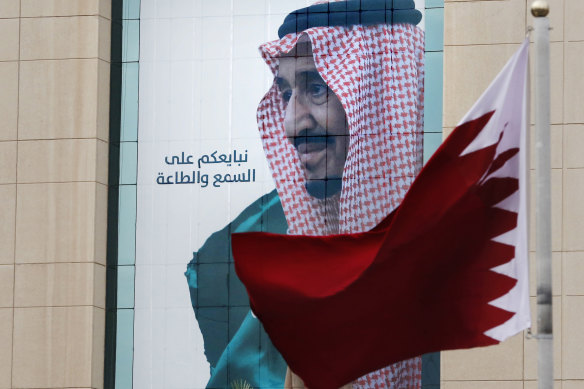 A Qatari flag flies in front of a banner portraying Saudi King Salman, in Riyadh, ahead of the Gulf states summit this week. 