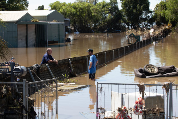 Two neighbours catch up as they survey wreckage around their homes.