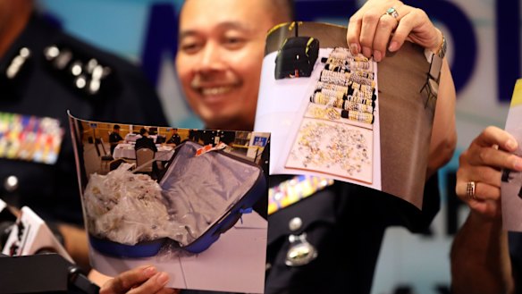 An officer of Malaysia's Federal Commercial Crime Investigation Department shows pictures of jewellery seized from Najib.