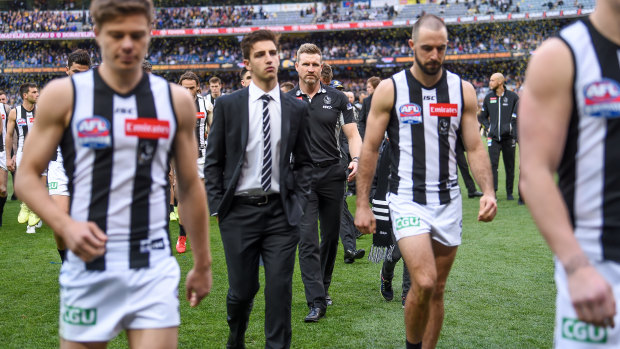 Nathan Buckley (centre back) and Collingwood players leave the field.