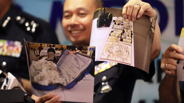 An officer of Malaysia's Federal Commercial Crime Investigation Department shows pictures of jewellery seized from Najib.