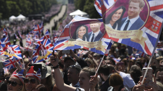 Royal fans wave flags as they wait for the newlyweds to go past after the wedding ceremony.