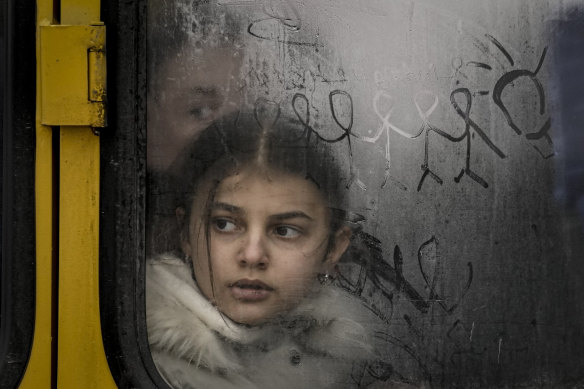 A child looks out a steamy bus window with drawings on it as civilians are evacuated from Irpin, Ukraine.