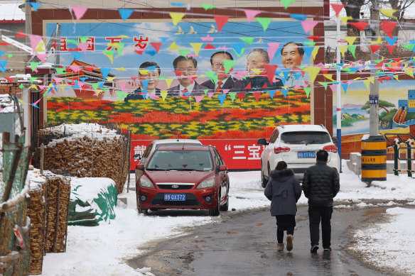 A couple walk by the portraits of former and current leaders of China in a village in Chicheng County, Hebei province.