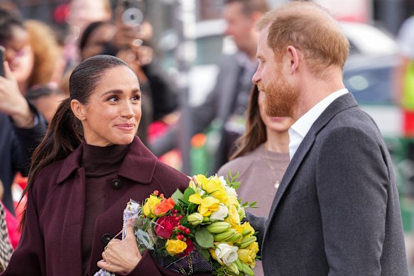 Meghan holds a bouquet of flowers from the crowd.